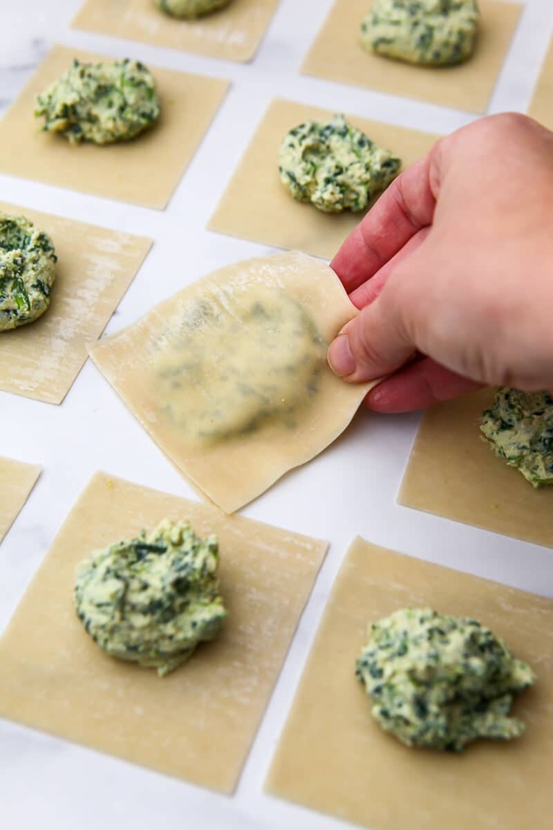 Setting down a finished homemade vegan ravioli among unfinished ones. 