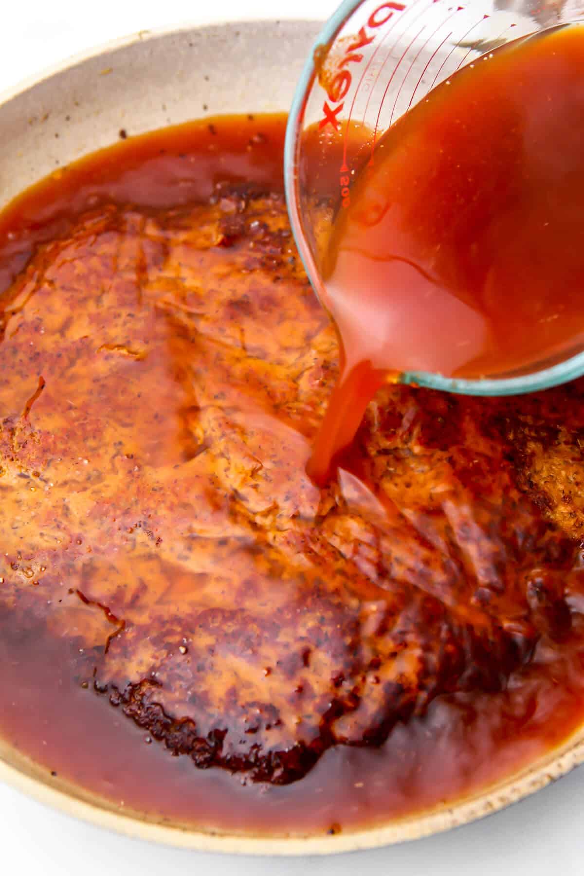 Broth being pour over a seared piece of seitan to make vegan ribs.