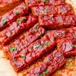 Vegan ribs smothered in BBQ sauce on a piece of parchment paper.