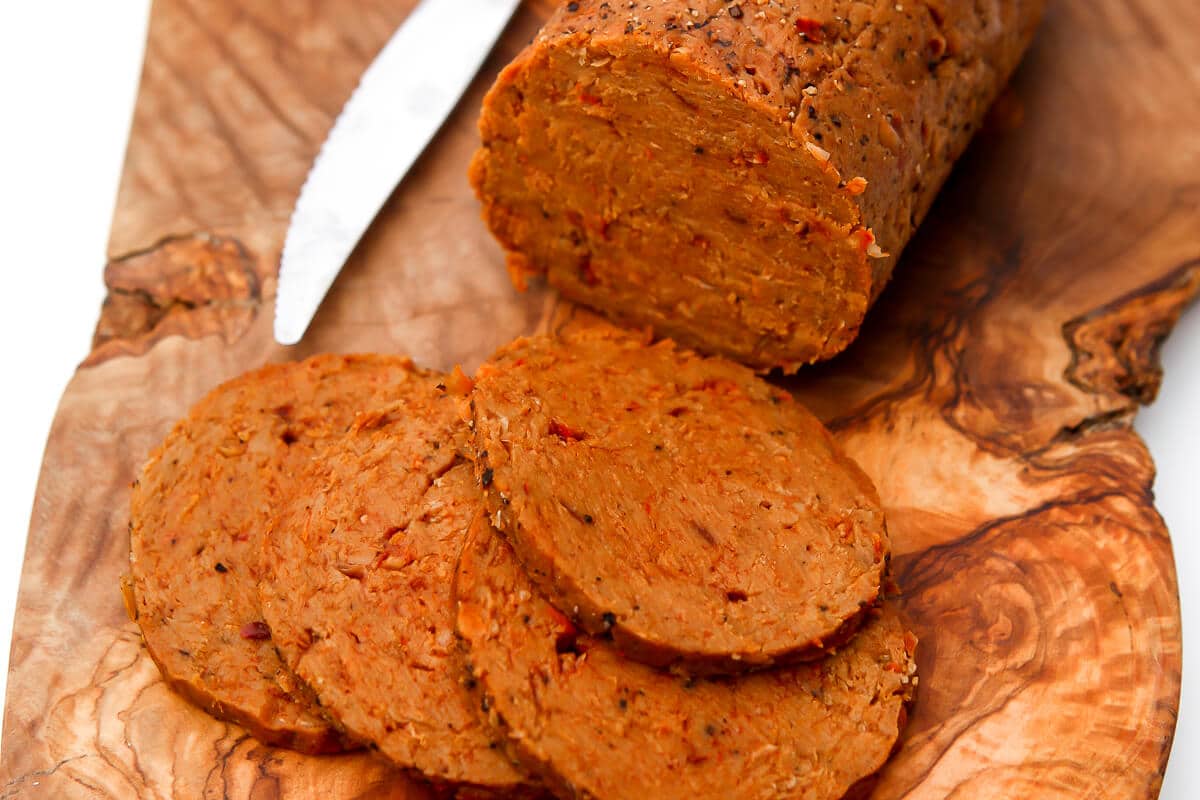 A close up of vegan salami slices on a cutting board.