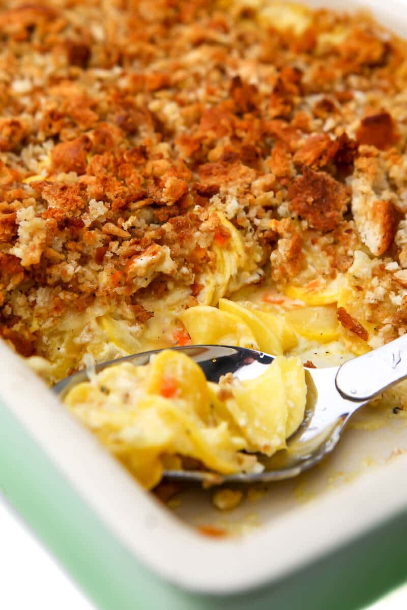 A close up of a vegan squash casserole with a piece taken out and a spoon in it.