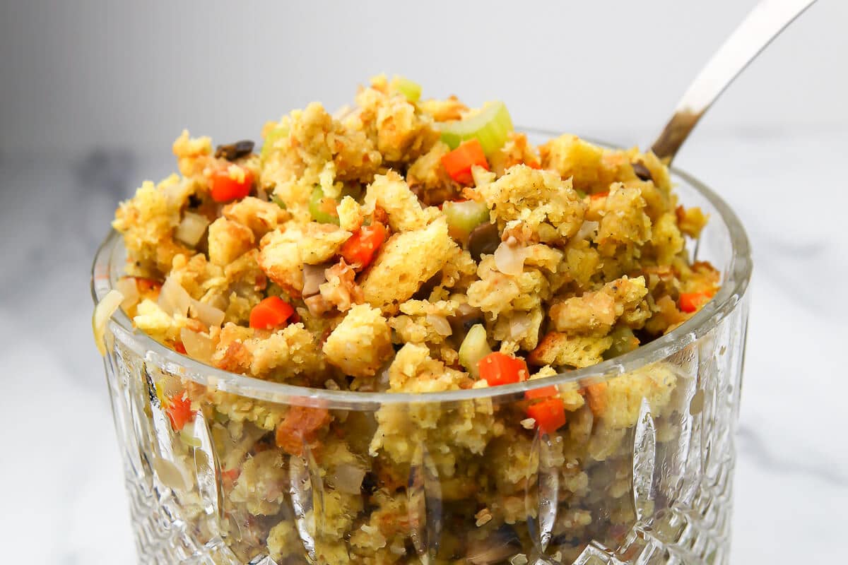 A bowl of vegan stuffing with a serving spoon in it.