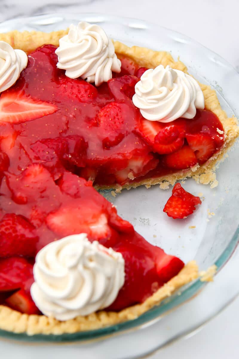 A Jello free strawberry pie with vegan whipped cream on top with a slice taken out.