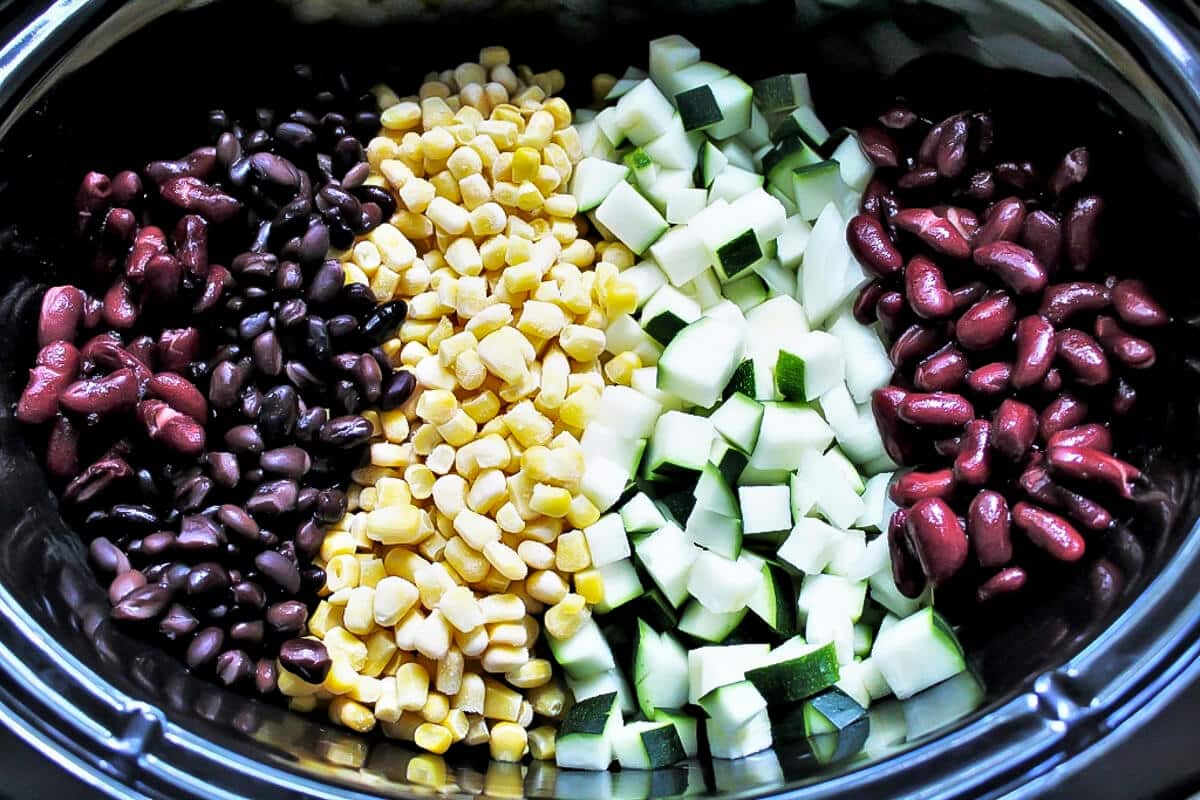 Beans, corn, and diced squash in a crock pot before cooking into taco soup.