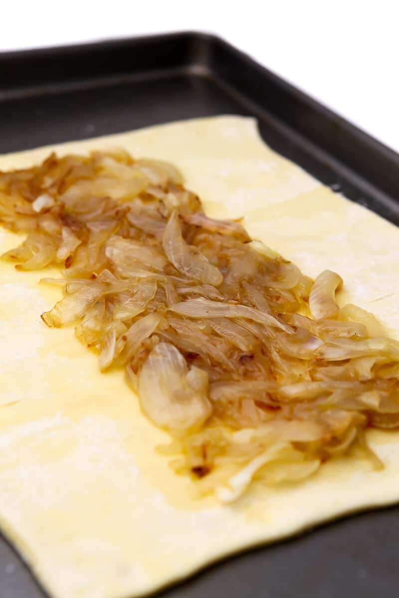 A layer of caramelized onions on a sheet of pastry puff on a cookie sheet.