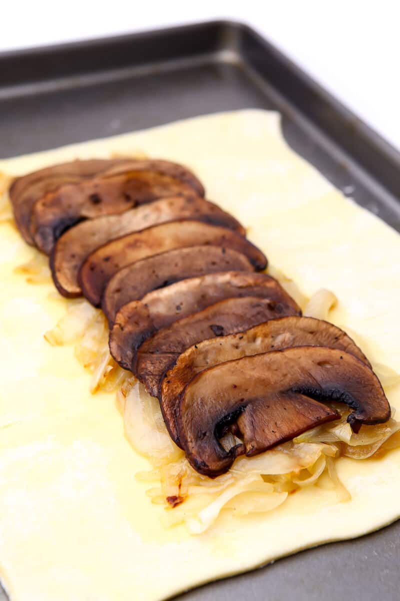A layer of vegan mushroom bacon on top of carnalized onions and pastry puff.