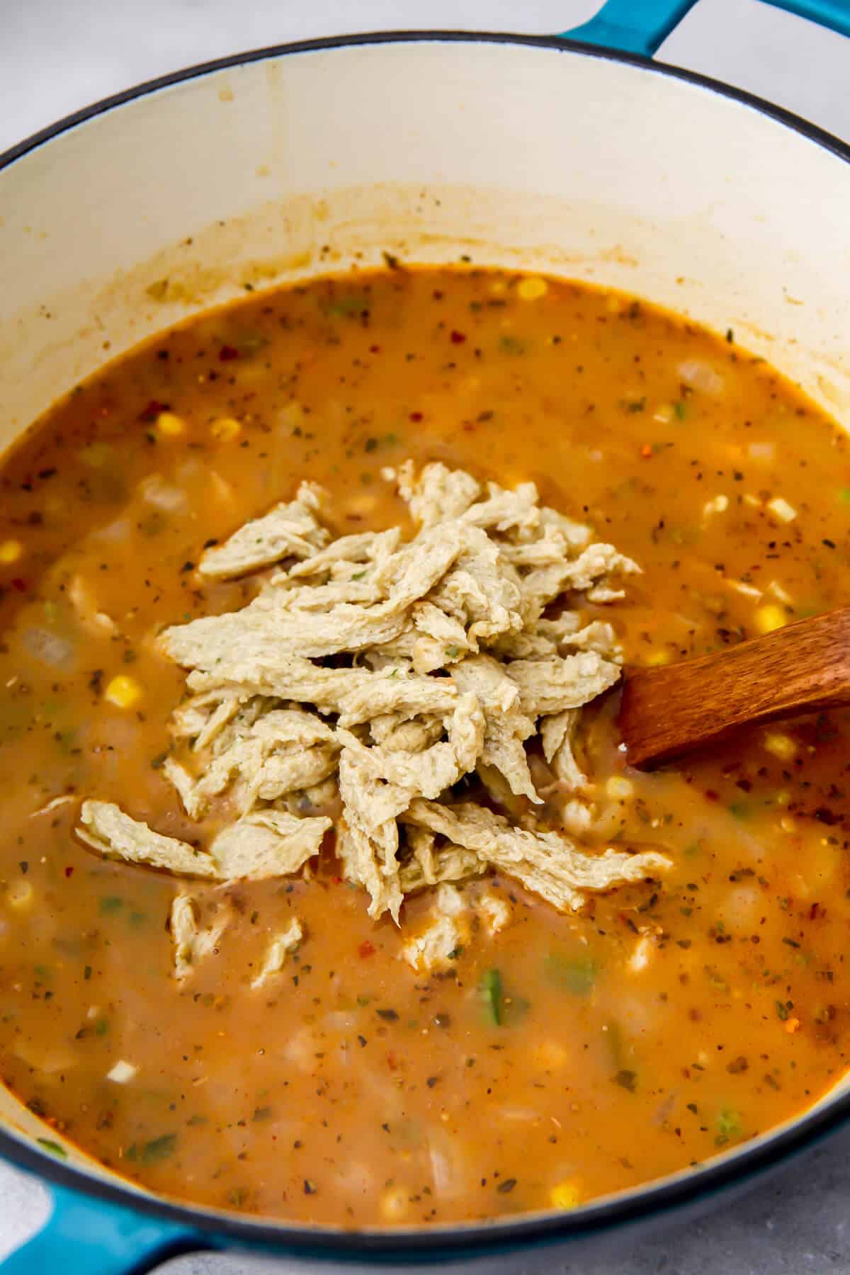 Shredded vegan chicken added to a pot of vegan white chili.