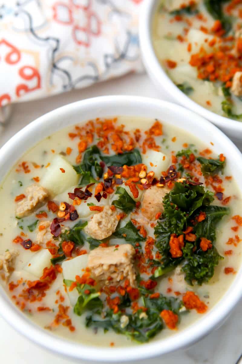 The top view of a bowl of Zuppa Toscana made vegan with vegan bacon bits sprinkled on top.