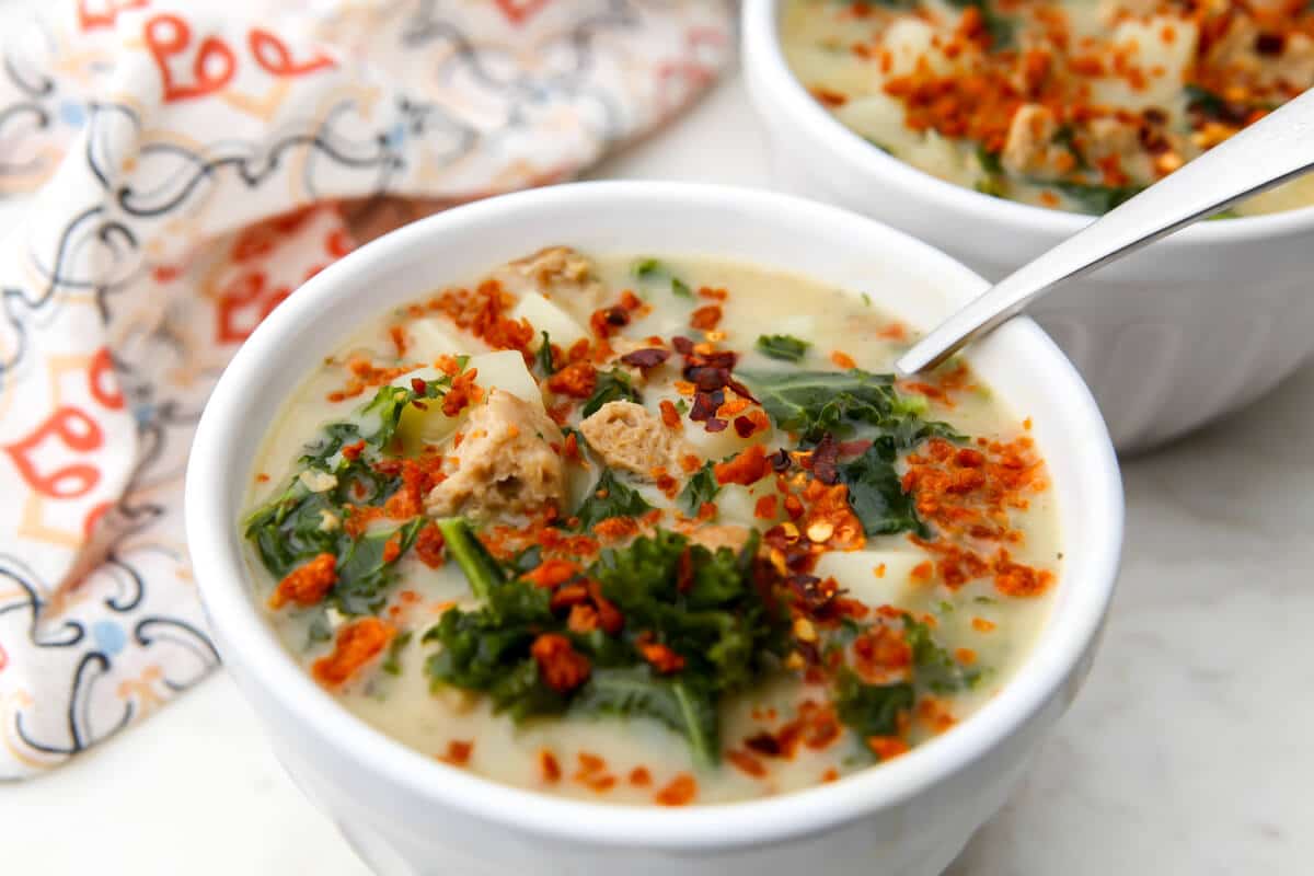 A  white bowl filled with meat free Zuppa Toscana with TVP bacon bits on top