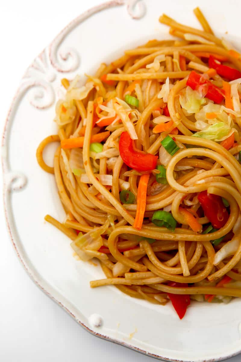 A top view of a white plate filled with vegetable Hakka noodles.