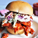 A gluten free vegan pulled pork sandwich made with soy curls and colorful vegan coleslaw.